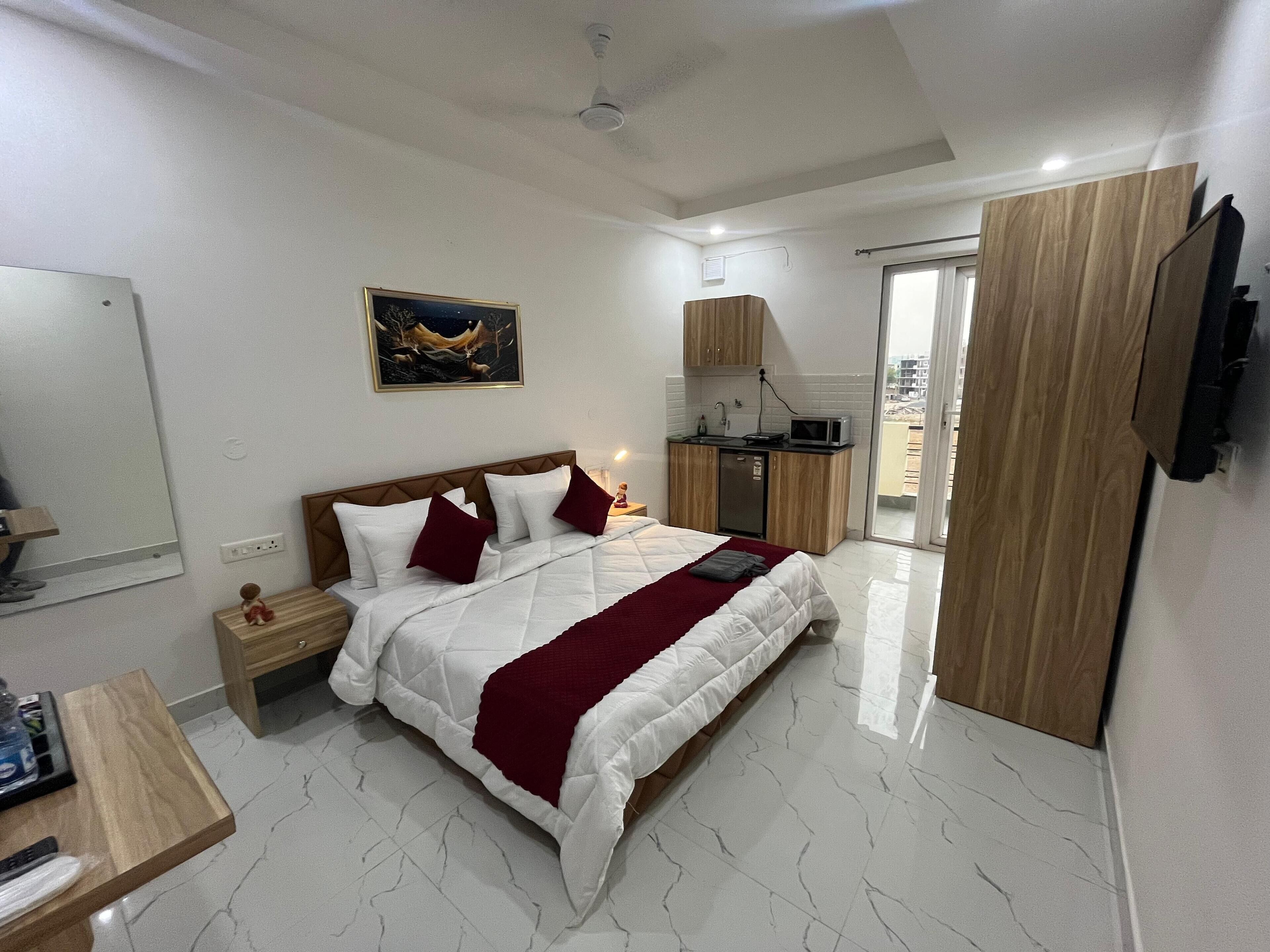 Une chambre comprenant un lit, une table de chevet, un bureau, un coin cuisine et un téléviseur.
