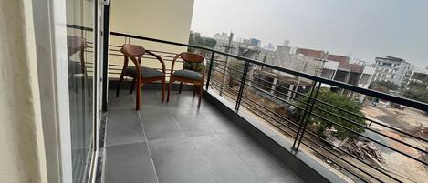 Un balcon avec deux chaises en bois et une porte vitrée.