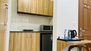 Una cocina compacta con armarios de madera, microondas, lavavajillas y una pequeña mesa con una silla.