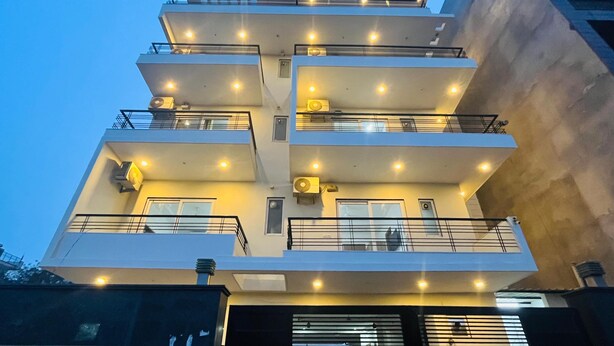 Un edificio de varios pisos con balcones, unidades de aire acondicionado y una entrada con reja.