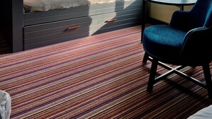 Une chambre moderne avec un canapé-lit, une petite table et une chaise. Une fenêtre offre une vue sur la verdure environnante.