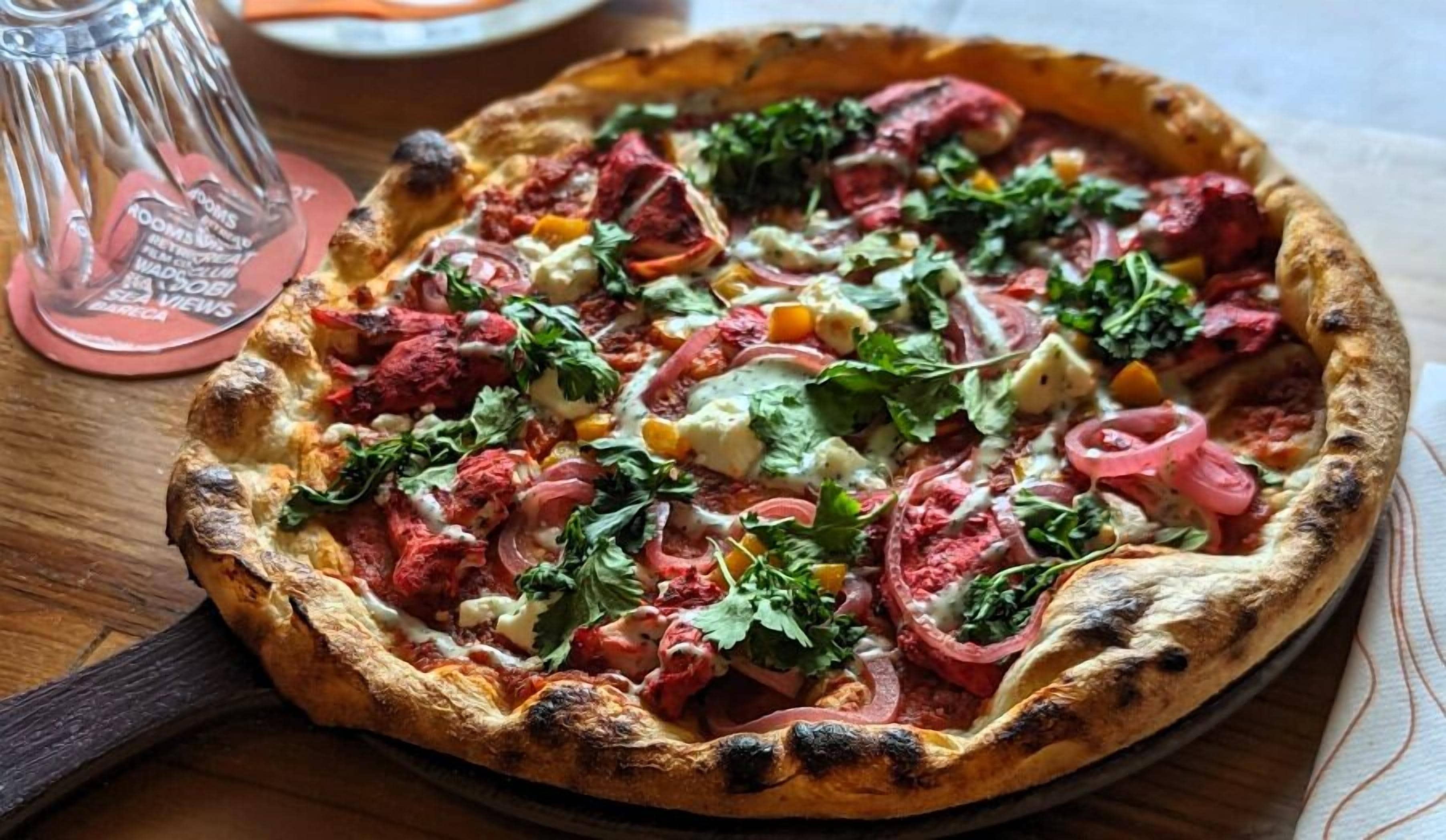 A pizza with various toppings on a wooden table.