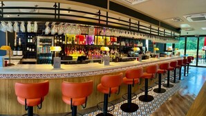 Un espace bar doté d’un long comptoir, de nombreux tabourets et d’une variété de bouteilles et de verres disposés sur des étagères.