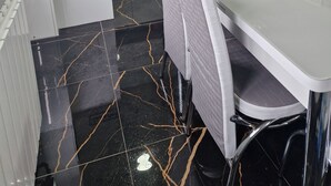 Una cocina moderna con armarios blancos, un salpicadero de azulejos negros y un suelo de mármol.