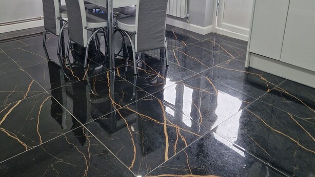Un comedor con una mesa blanca y cuatro sillas, una cocina con armarios blancos y una ventana con cortinas.