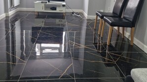 Una sala de estar moderna con televisor de pantalla plana, dos sillones de cuero y piso de mármol.
