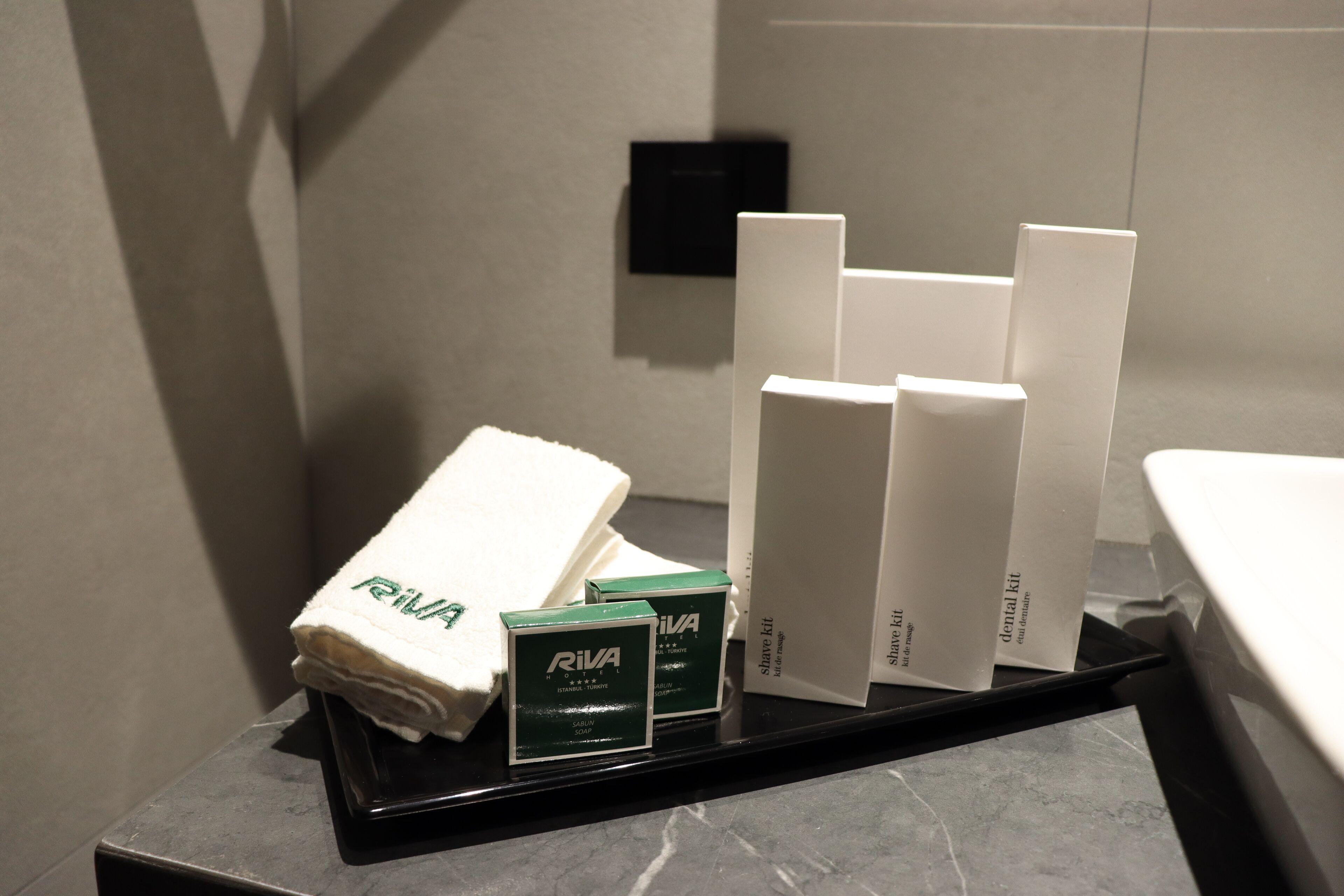 A bathroom counter with a folded towel and several toiletries, including a dental kit and a razor.