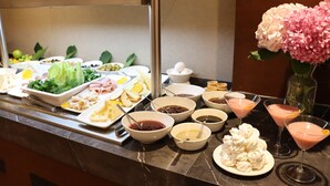 Un bufé con diferentes opciones de comida y bebidas, incluyendo platos de queso, frutas y una variedad de salsas.
