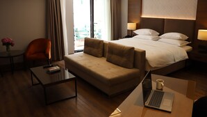 Una habitación de hotel con una cama, un sofá, una mesa de centro, una computadora portátil y una silla.