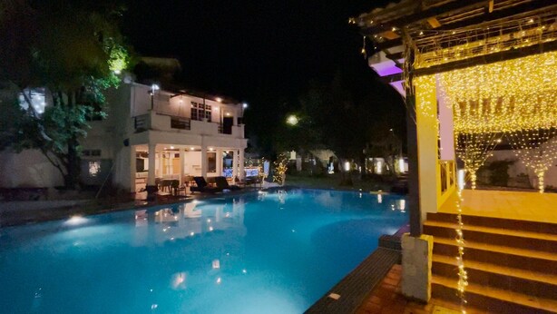 A swimming pool at night with a building in the background and string lights. - Seremban Grande Villa by uBook (Seremban)