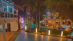 A nighttime view of a hotel courtyard with a pool, palm trees, and illuminated structures. - Seremban Grande Villa by uBook (Seremban)