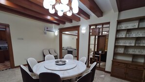 A dining area with a round table, six chairs, and a decorative ceiling light. - Seremban Grande Villa by uBook (Seremban)