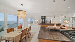 A spacious kitchen with a large island, modern pendant lights, and a view of the ocean. - Waterfalling Estate is an oceanfront compound on the Big Island unlike any other (Ninole)