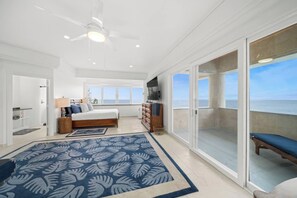 A spacious bedroom with a large bed, a ceiling fan, and a view of the ocean through a sliding glass door. - Waterfalling Estate is an oceanfront compound on the Big Island unlike any other (Ninole)