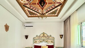 A bedroom with a patterned ceiling, a bed with a green and white headboard, and a bench. - Capsa Thermal Oasis (Gafsa)