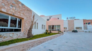 A building with stone and modern architectural elements, a parking area, and flags. - Capsa Thermal Oasis (Gafsa)