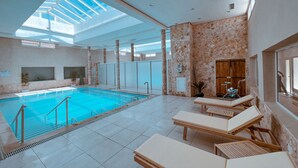 An indoor swimming pool with a skylight, tiled floor, and lounge chairs. - Capsa Thermal Oasis (Gafsa)