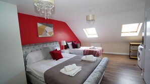 A bedroom with two beds, a chandelier, a ceiling fan, and a washing machine. - 59B Comfortable Home Sleeps 8 (Hounslow)