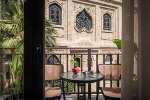 A balcony with wicker chairs, a small table, and a potted plant. - Centro Vero Suites by Omilos Hotels (Heraklion)