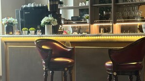 A bar area with two leather chairs, a coffee machine, and shelves with glassware. - Room-viareggio Old Style Sea View (Viareggio)