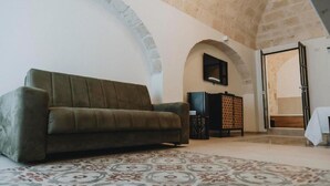 Un salon avec un canapé, un tapis à motifs et un téléviseur fixé au mur.