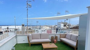 Une terrasse sur le toit, aménagée avec deux canapés et une table, le tout entouré de gazon synthétique.