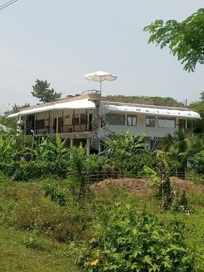 A two-story building with a white exterior and a staircase leading to the upper floor. - Matsya Island Retreat (Port Blair)