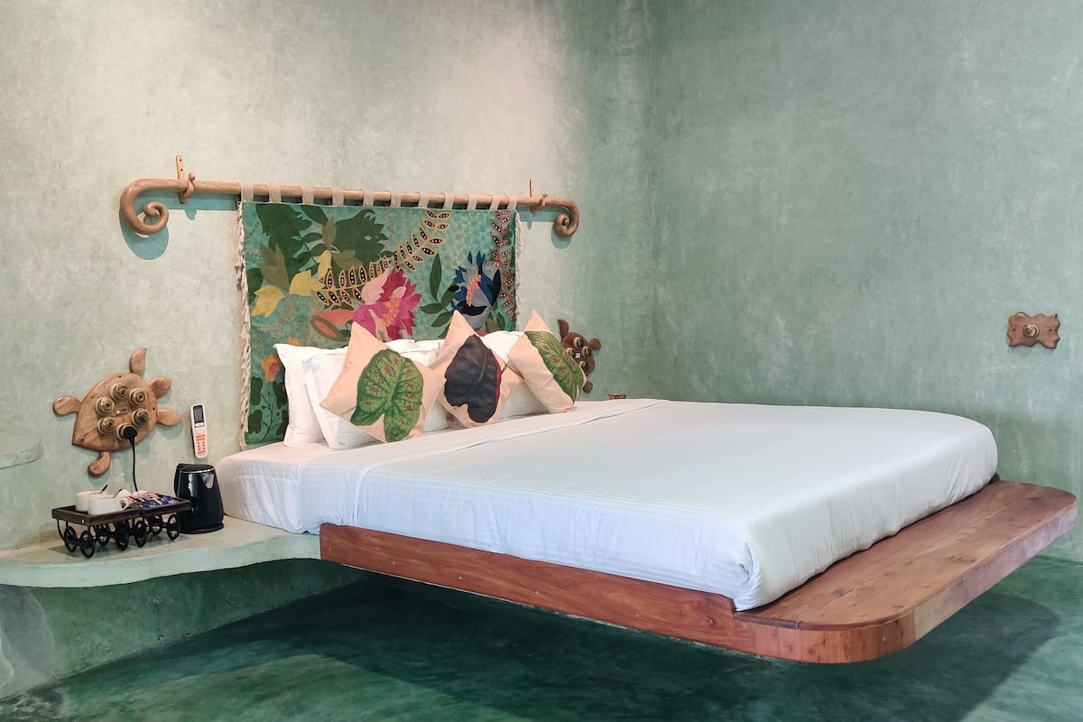 Quarto com cama, mesa de cabeceira, ar-condicionado fixado na parede e cabeceira decorativa.