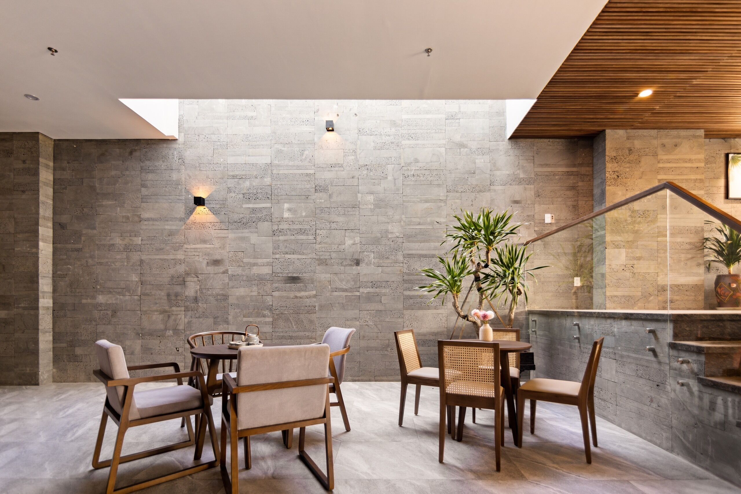 Ein modernes Interieur mit einer Steinwand, Holzmöbeln und einer Treppe.