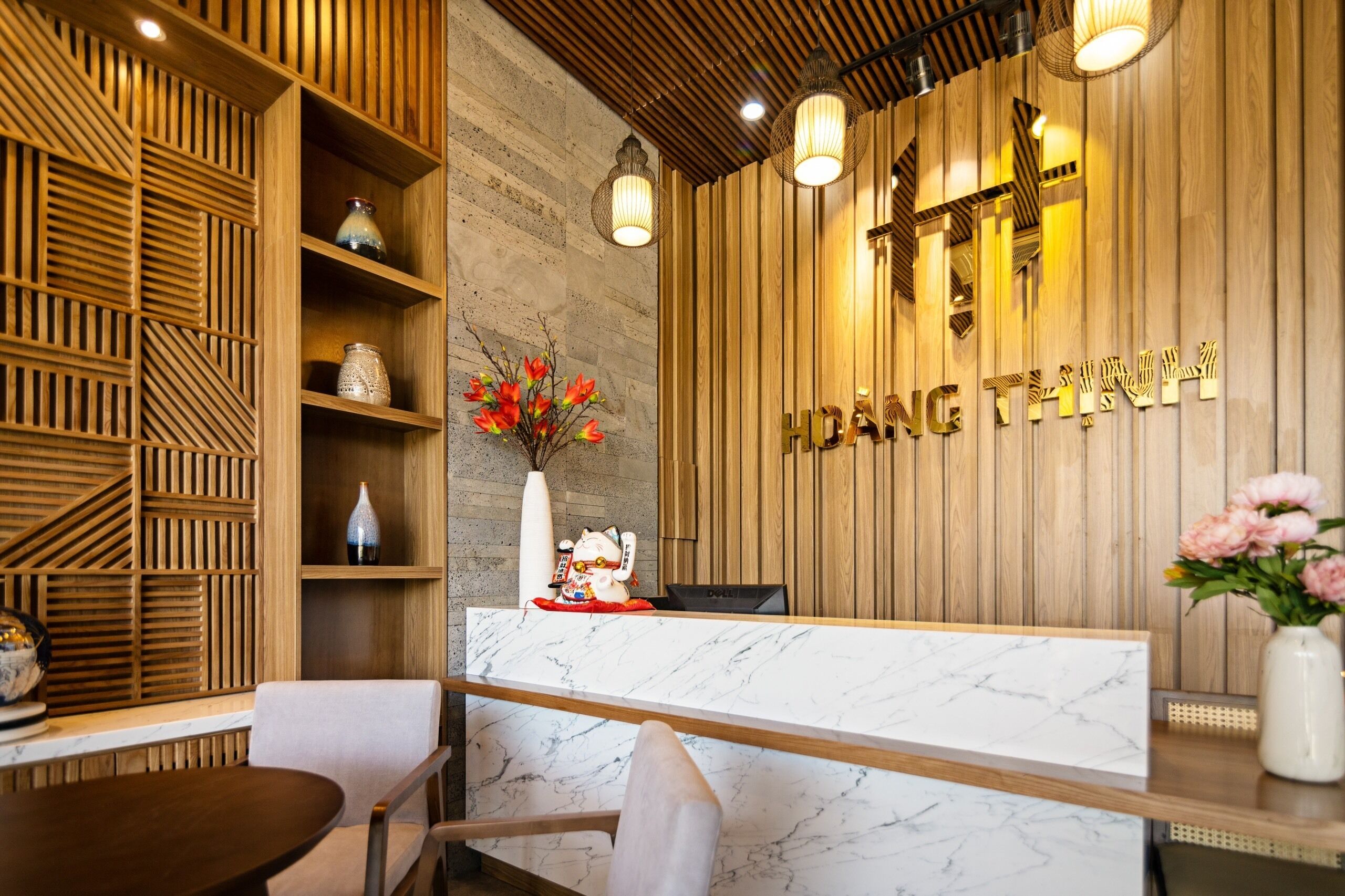 A reception desk with a wooden panel wall, a marble counter, and a decorative vase with flowers.