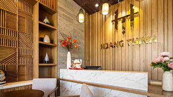 A reception desk with a wooden panel wall, a marble counter, and a decorative vase with flowers.