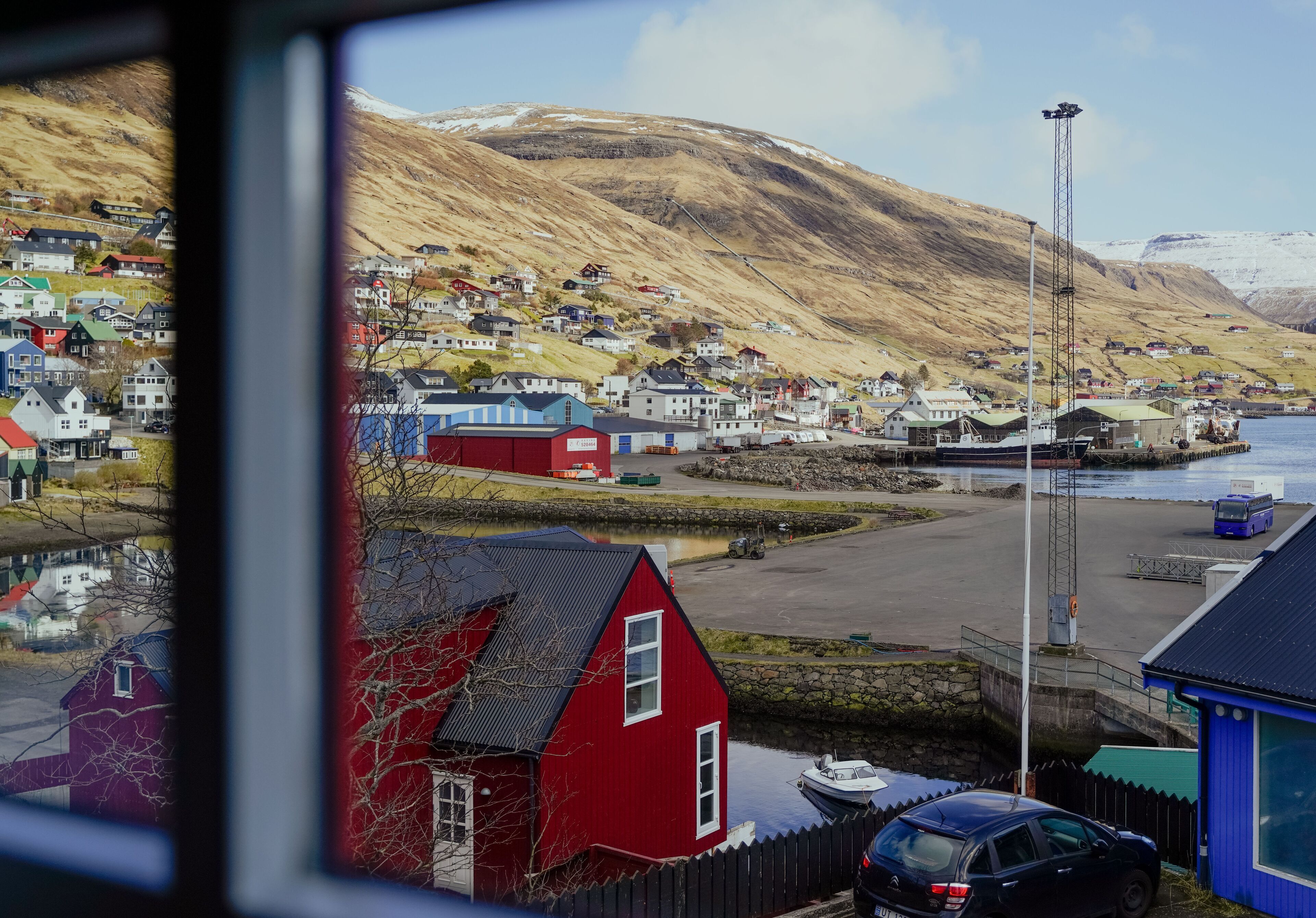A coastal town with houses, a dock, and a mountain in the background.