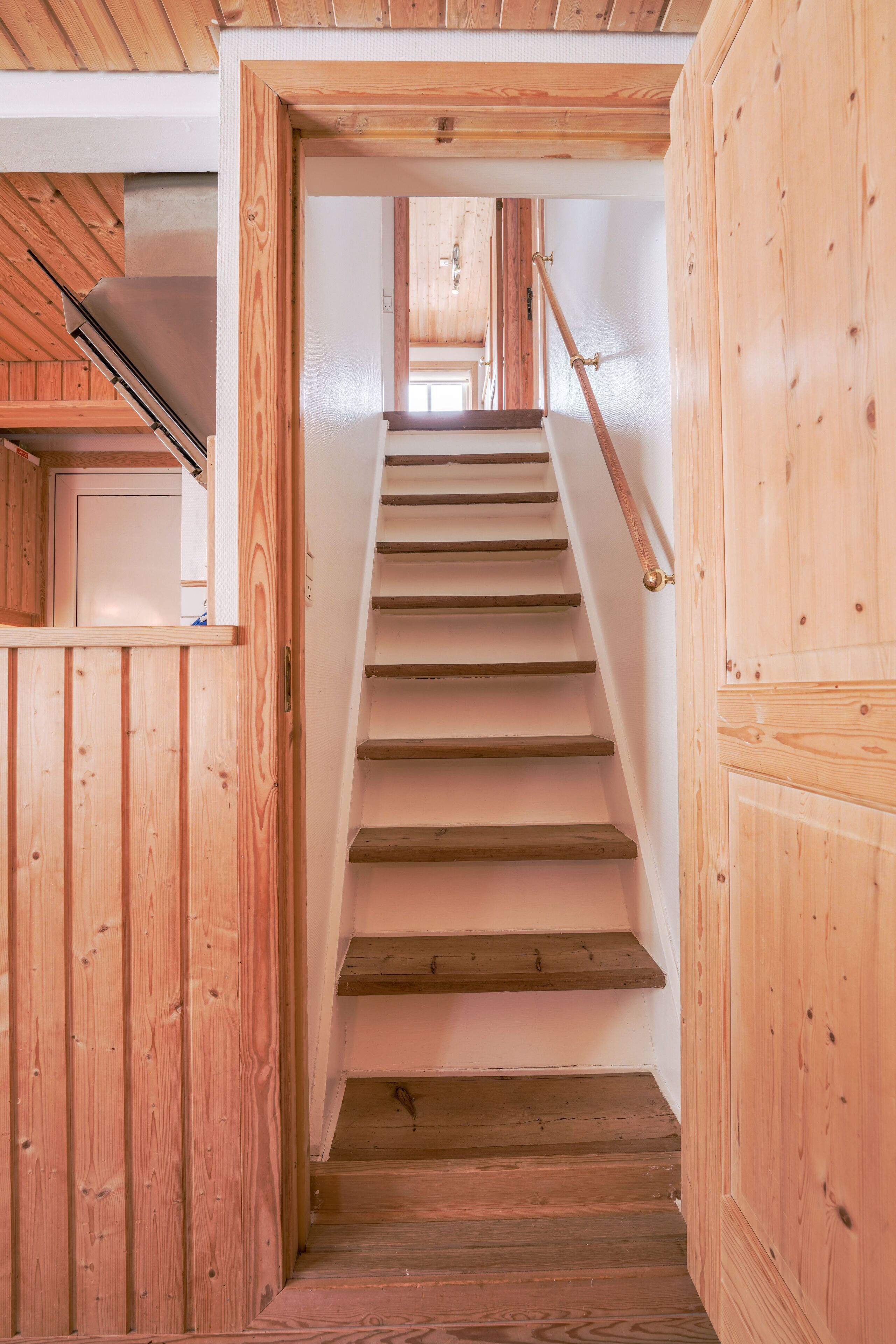 Una scala in legno con corrimano che conduce a un piano superiore.