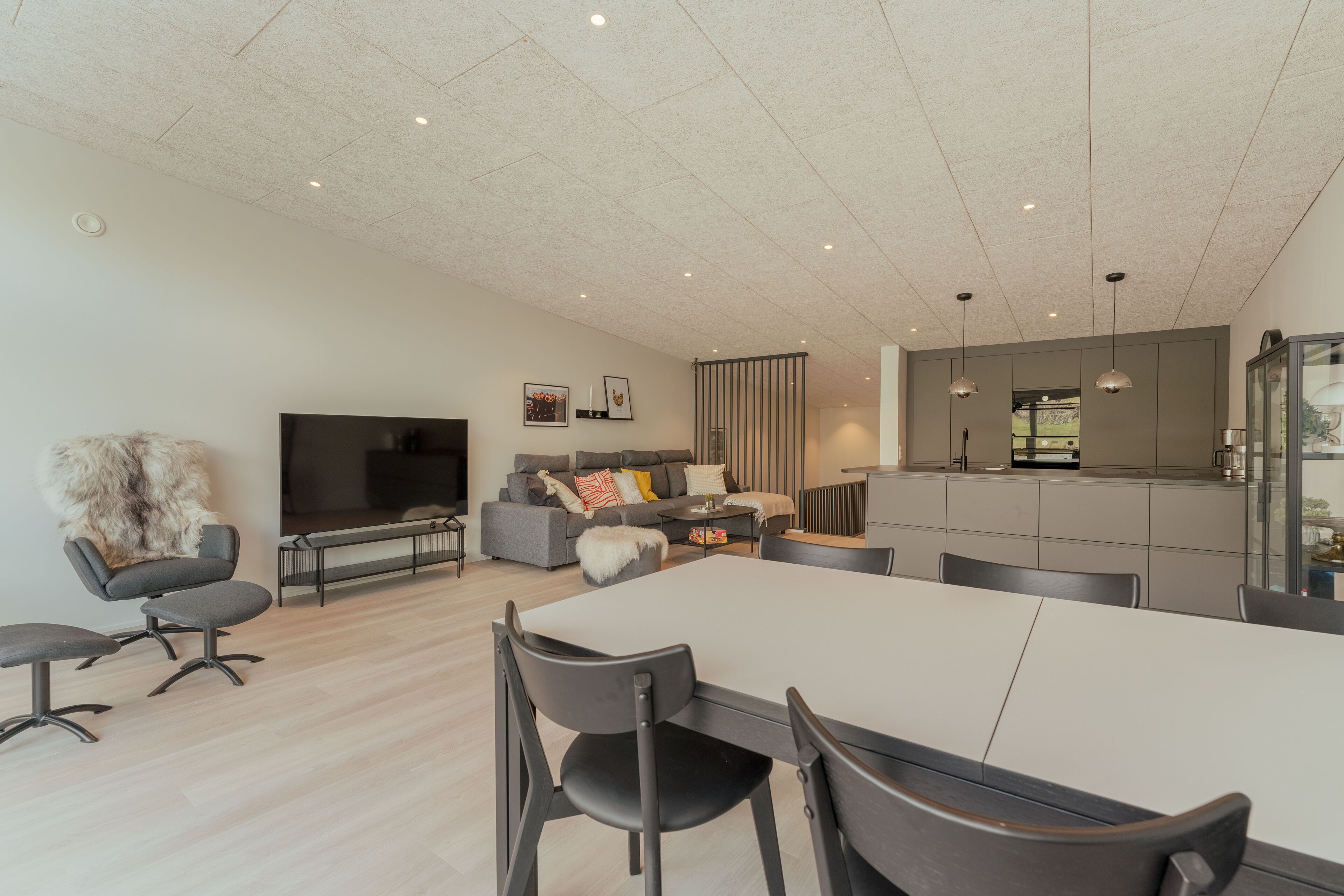 A modern living room with a sofa, TV, and dining area.