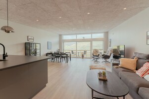A spacious living area with a large window, a dining area with chairs, a sofa, and a coffee table.