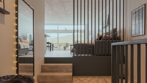 A modern interior with a wooden floor, a black bench, a staircase, and a view of the outdoors. - Luxurious Waterfront Retreat | Spectacular Views (Vestmanna)
