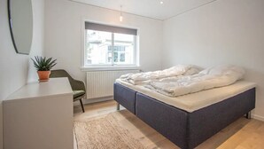 A bedroom with a bed, a desk, a chair, a potted plant, and a window. - Lovely Apartment In The Heart Of Tórshavn (Tórshavn)