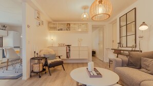 A modern living room with a sofa, coffee table, and a dining area with a table and chairs.