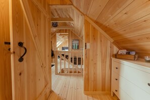 A wooden interior with a staircase leading to an upper level, a white dresser, and a small shelf with items. - Seaside Escape - 2 Bedroom Home With Stunning Views (Velbastaður)