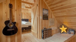 Un intérieur en bois avec une guitare, un lit, une décoration en forme d’étoile et une petite table sur laquelle se trouve un livre.