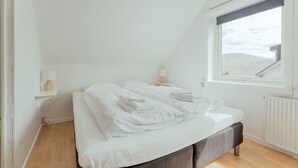 Ett sovrum med en säng, sängbord och ett fönster med utsikt över en bro.