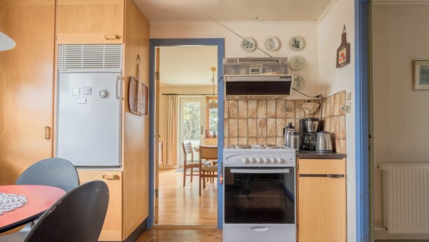 A compact kitchen with a refrigerator, stove, and dining area with chairs and a table. - Charming 2-Bedroom Home | 20 Min Walk To City Centre (Tórshavn)