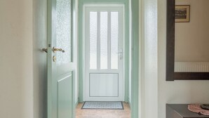 A hallway with a light-colored wooden floor, a green door, and a dark wooden bench. - Charming 2-Bedroom Home | 20 Min Walk To City Centre (Tórshavn)