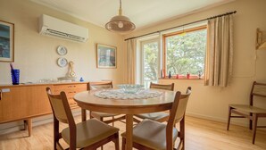 A dining area with a round wooden table, six chairs, a central glass bowl, and a pendant light. - Charming 2-Bedroom Home | 20 Min Walk To City Centre (Tórshavn)
