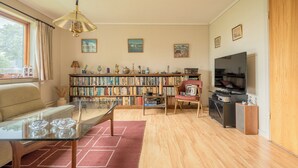 A living room with a sofa, coffee table, bookshelf, television, and a wooden cabinet. - Charming 2-Bedroom Home | 20 Min Walk To City Centre (Tórshavn)