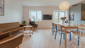 A modern living room with a sofa, chairs, a dining table, and a kitchen area. - Charming Central Tórshavn Retreat - 2Br Apartment (Tórshavn)