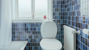 Un baño con inodoro, bañera y ventana.