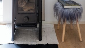 Una sala de estar moderna con un estufa de leña negra, un espejo grande y un cuadro en la pared.