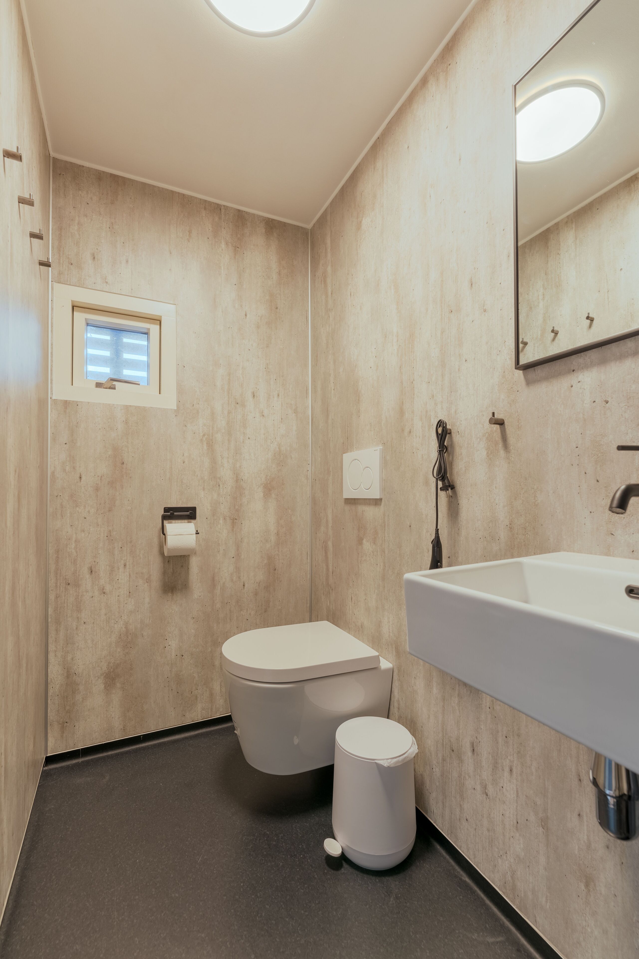A bathroom with a toilet, sink, and mirror.