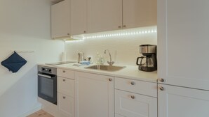 Eine moderne Küche mit weißen Schränken, einem Backofen, einer Spüle und einer Kaffeemaschine.